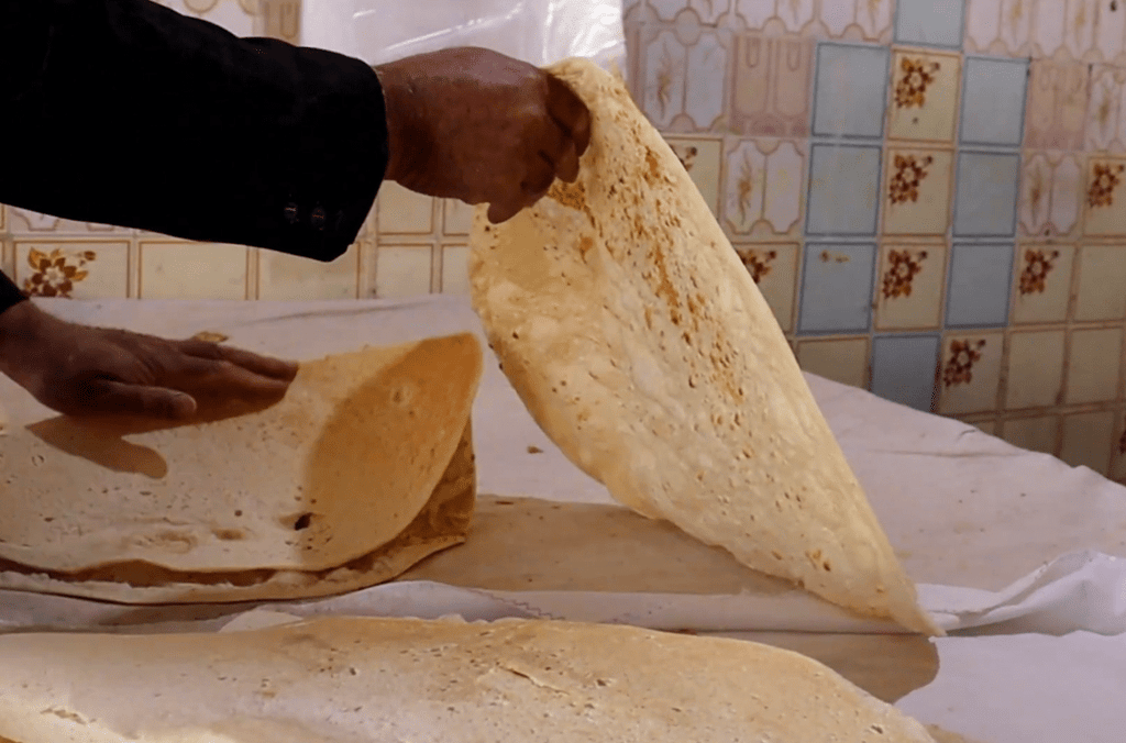 Hand holding a large flatbread, part of a humanitarian effort providing sustenance and hope to Palestinians. Crypto donations like USDT support this vital aid.