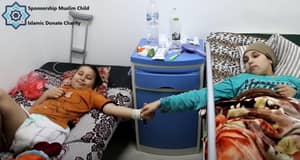 Two children lie in hospital beds, one smiling and holding the other's hand, symbolizing hope and resilience in care supported by BTC donations.