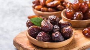 A few wooden bowls filled with dates. One bowl in the foreground has a green leaf.