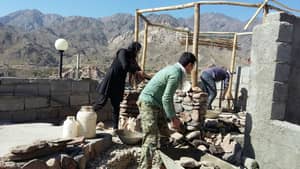 Rebuilding efforts in a mountainous region with men and women working on construction, implying crypto-funded aid via Bitcoin-cash donations.