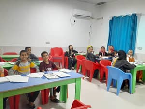 Children in a classroom, smiling and learning, supported by crypto Khums donations for education.