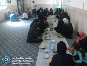 Group of people, some men and women, sitting on the floor gathered around a long table for a meal. This event is supported by crypto donations, providing hot meals for families. Key elements: daily charity, relief for the needy, sustainable livelihoods, hot meals, Islamic relief, aid provision, with support via ETH.