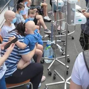 Children receiving IV treatment, some with shaved heads, sit with caregivers near medical equipment, indicating urgent need for aid via crypto donation, like ETH.