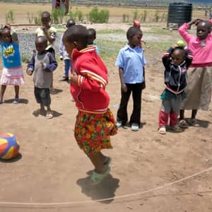 Children playing leapfrog outdoors with a ball, benefiting from crypto donations via USDT, supporting education for 49 orphans.