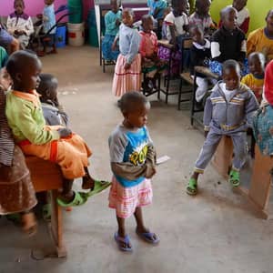 A group of orphaned children sit and stand, receiving educational support through crypto donations, including 49 children sponsored in the 2023-2024 academic year, with an emphasis on ETH-supported aid.