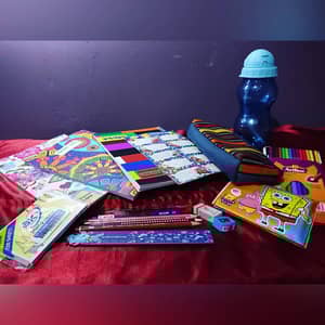Colorful school supplies including notebooks, pencils, a pencil case, and a water bottle. This donation, facilitated by crypto via BTC, provides education for disadvantaged children.