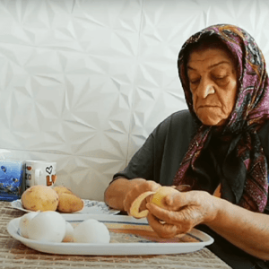 Elderly woman wearing a headscarf peeling potatoes, a symbol of wisdom and experience, with support from crypto donations like ETH.