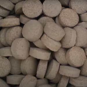 Pile of small, light brown, circular, and cylindrical tablets, possibly compressed nutrients or fodder, representing vital resources funded by crypto donations like BTC for families.