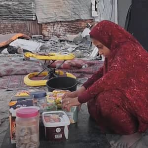 A child in a red headscarf sorts through donated food items, including dried goods and packaged snacks, in a makeshift shelter. This image highlights the plight of working children and the need for aid, supported by ETH donations.
