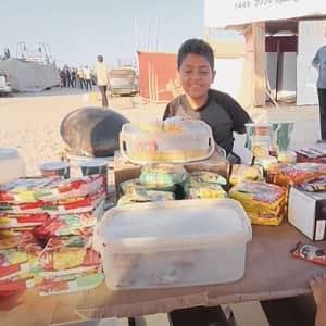 A smiling boy works at a stall selling food and snacks, Universal Children's Day focus on working children, with donations supported by BTC.