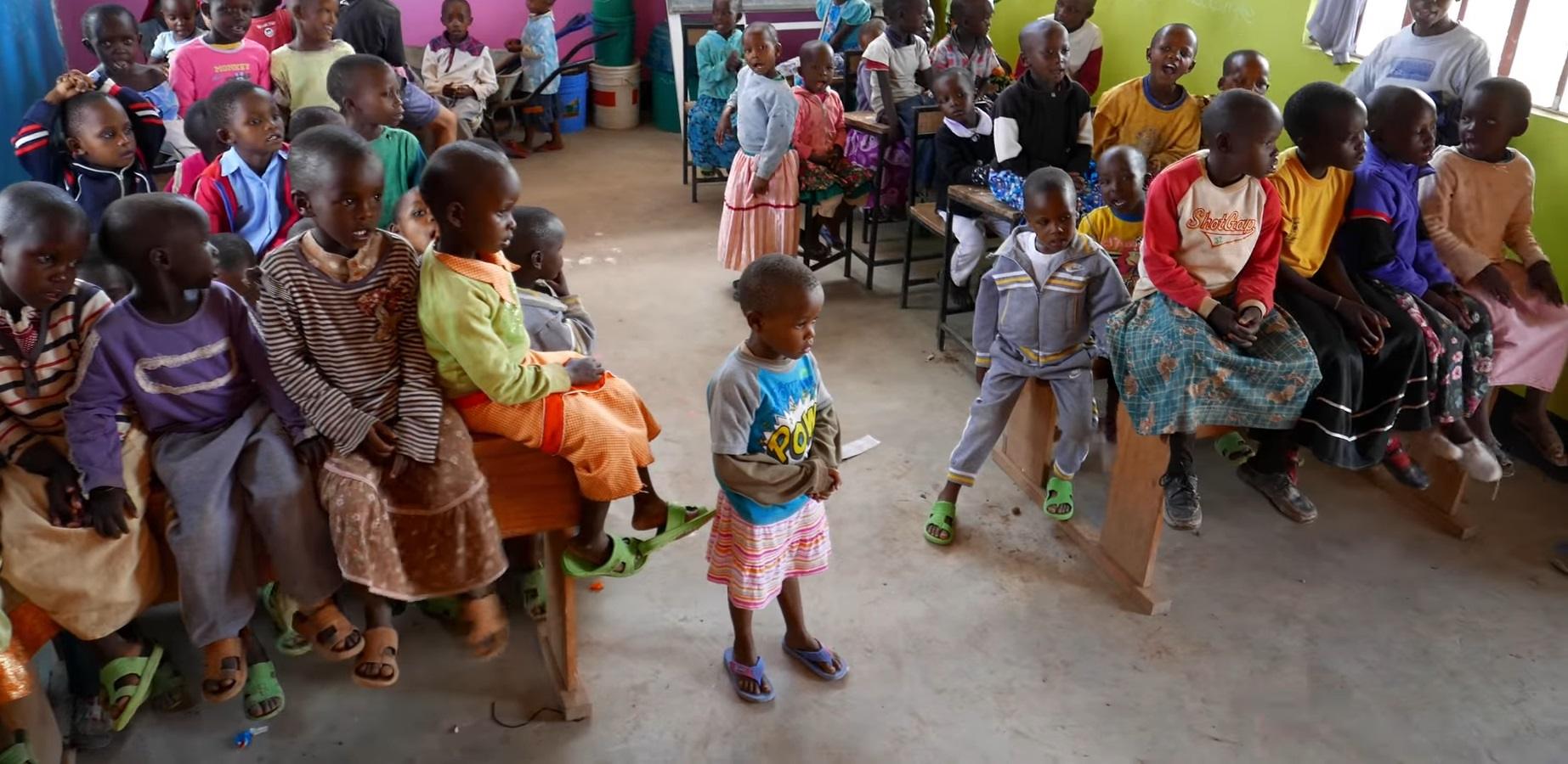 A group of orphaned children sit and stand, receiving educational support through crypto donations, including 49 children sponsored in the 2023-2024 academic year, with an emphasis on ETH-supported aid.