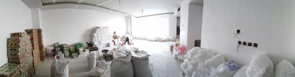 أكوام من المواد الغذائية والأكياس في غرفة تخزين، جاهزة للتوزيع، مما يشير إلى مساعدات إنسانية مدعومة بالعملات المشفرة عبر RLUSD.