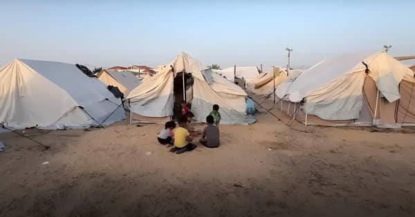 Children in a refugee camp with tents in the background, urgent need for aid. Your crypto donation, processed via Solana, provides food, water, and medical relief to displaced families in Rafah.