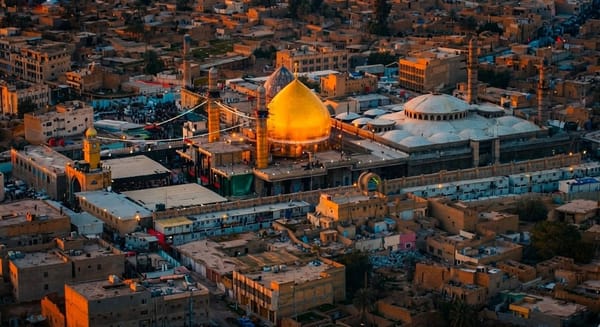 Golden domed shrine with minarets surrounded by a cityscape at sunset. Features Imam al-Hadi's legacy of charity and transparency, accepting crypto donations like USDT.