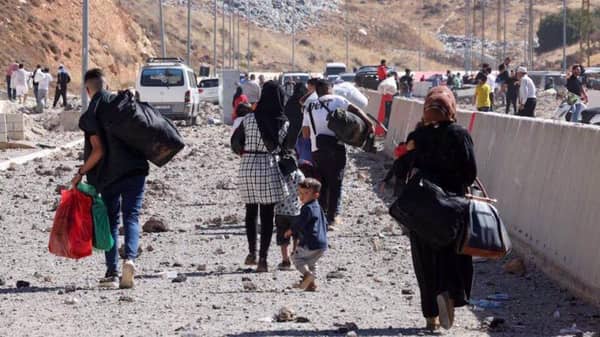 Baalbek Lebanon crisis: Displaced families, including vulnerable women and children, walk with belongings. Donate crypto like USDT for essential aid, food, and shelter to support the Muslim Ummah facing conflict and displacement.