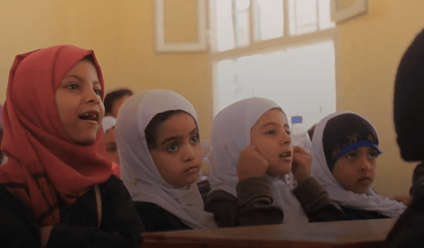 Young Yemeni schoolgirls in hijabs listen intently in a classroom, their education supported by crypto donations enabling access to laptops and the internet.