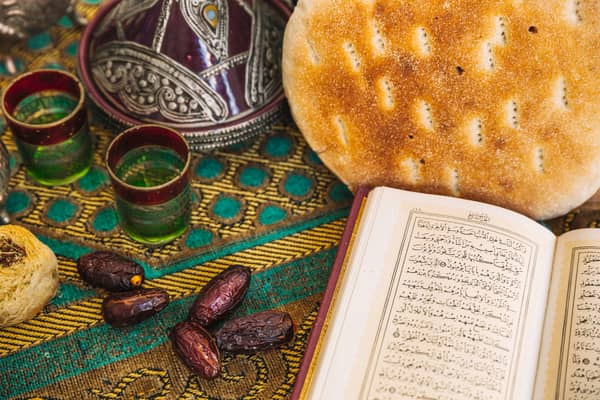 Ramadan meal setting with dates, bread, tea, and an open Quran. Pay Kaffara with Bitcoin for religious obligations.
