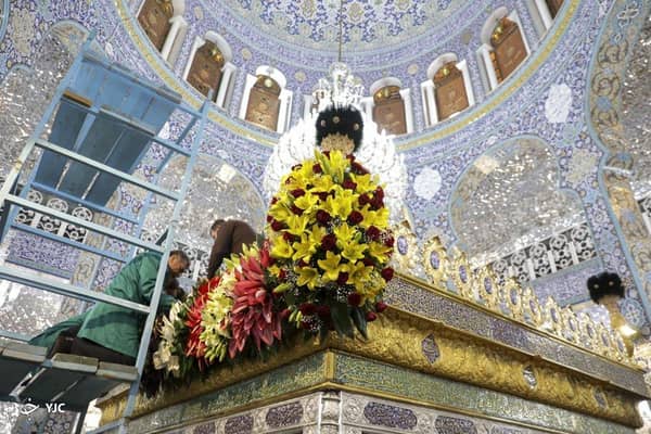 Preparations for a Shia Muslim religious event, with a large floral arrangement on a golden structure, supported by crypto donations via USDT.
