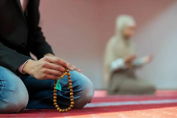 Woman praying with prayer beads, symbolizing seeking forgiveness for sins and achieving true repentance through Islamic charity and crypto donations, supported by ETH.