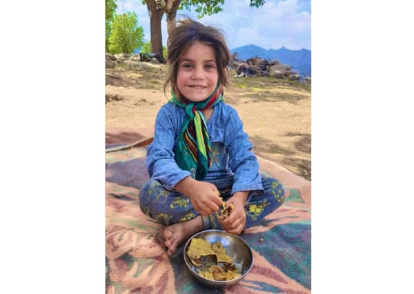 Smiling young Fuqara child eating from a bowl, recipient of crypto zakat funds. Crypto donations via XRP help provide sustenance.