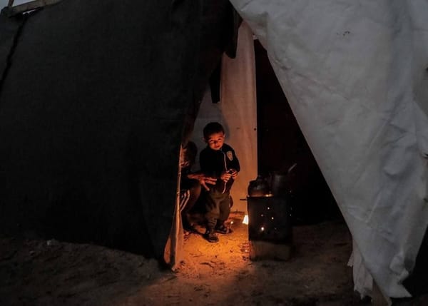 Children huddle inside a tent near a wood-burning stove, receiving warmth and aid through charitable donations received via crypto like ETH.