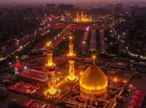 Virtual tour of Imam Hussain Holy Shrine at night, illuminated with festive lights, showcasing its grand golden dome and minarets with crowds gathered below. Donations supported by XRP.