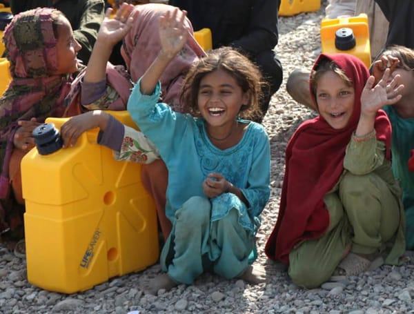 Children holding water containers with smiles. Donation via cryptocurrency for clean water projects. Sadaqah Jariyah impacts lives.