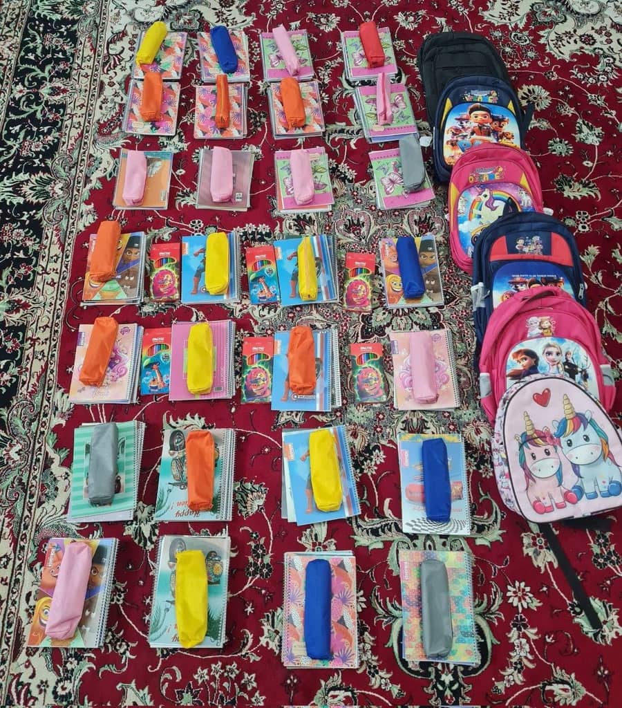 School supplies including backpacks, notebooks, and pencil cases arranged on a rug, ready for donation to support education, with transactions processed via crypto, such as SOL.